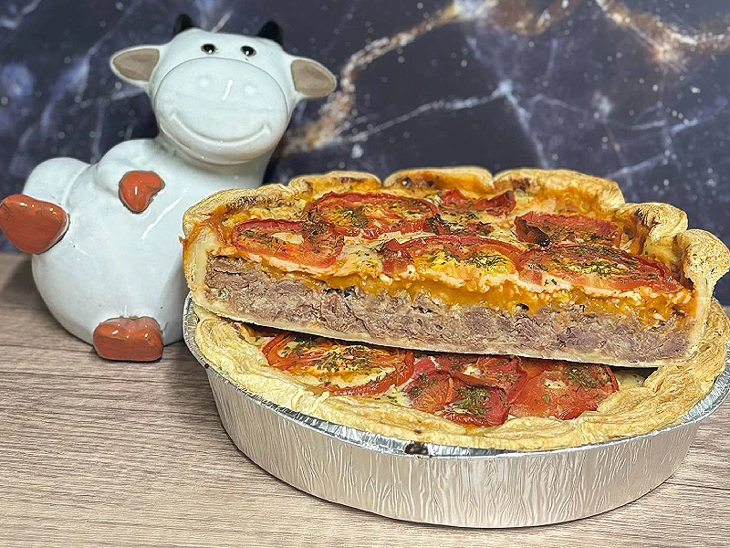 Tarte à la viande avec tomates et figurine de vache